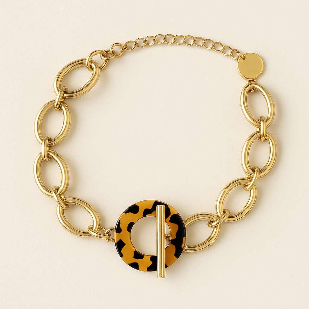 Bracelet Ndomo – mailles dorées en acier inoxydable et fermoir écaille, photographié sur fond beige chaud texturé.