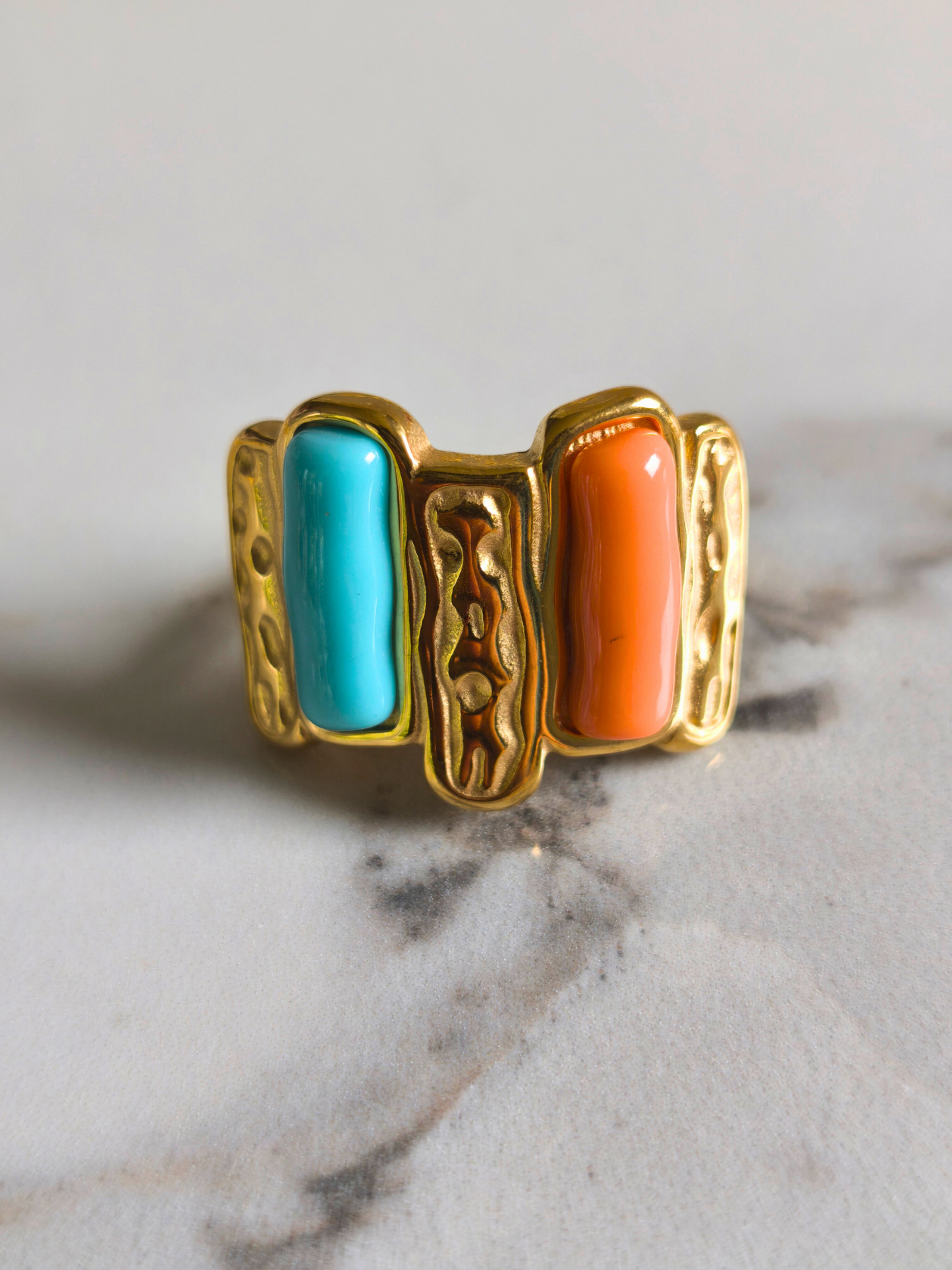 Vue de face de la bague Madras en acier doré, émaillée turquoise et orange