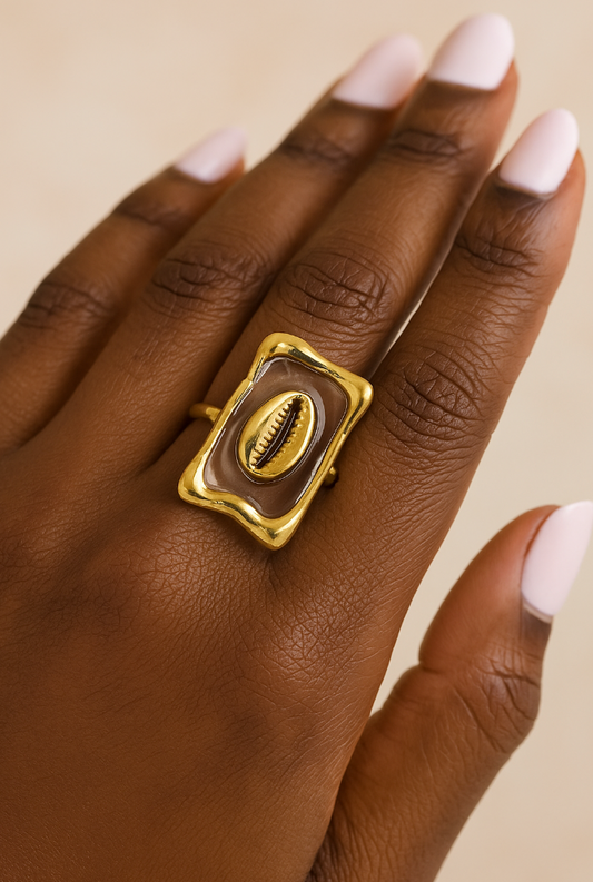 Bague Yéné portée sur main féminine, design cauri doré
