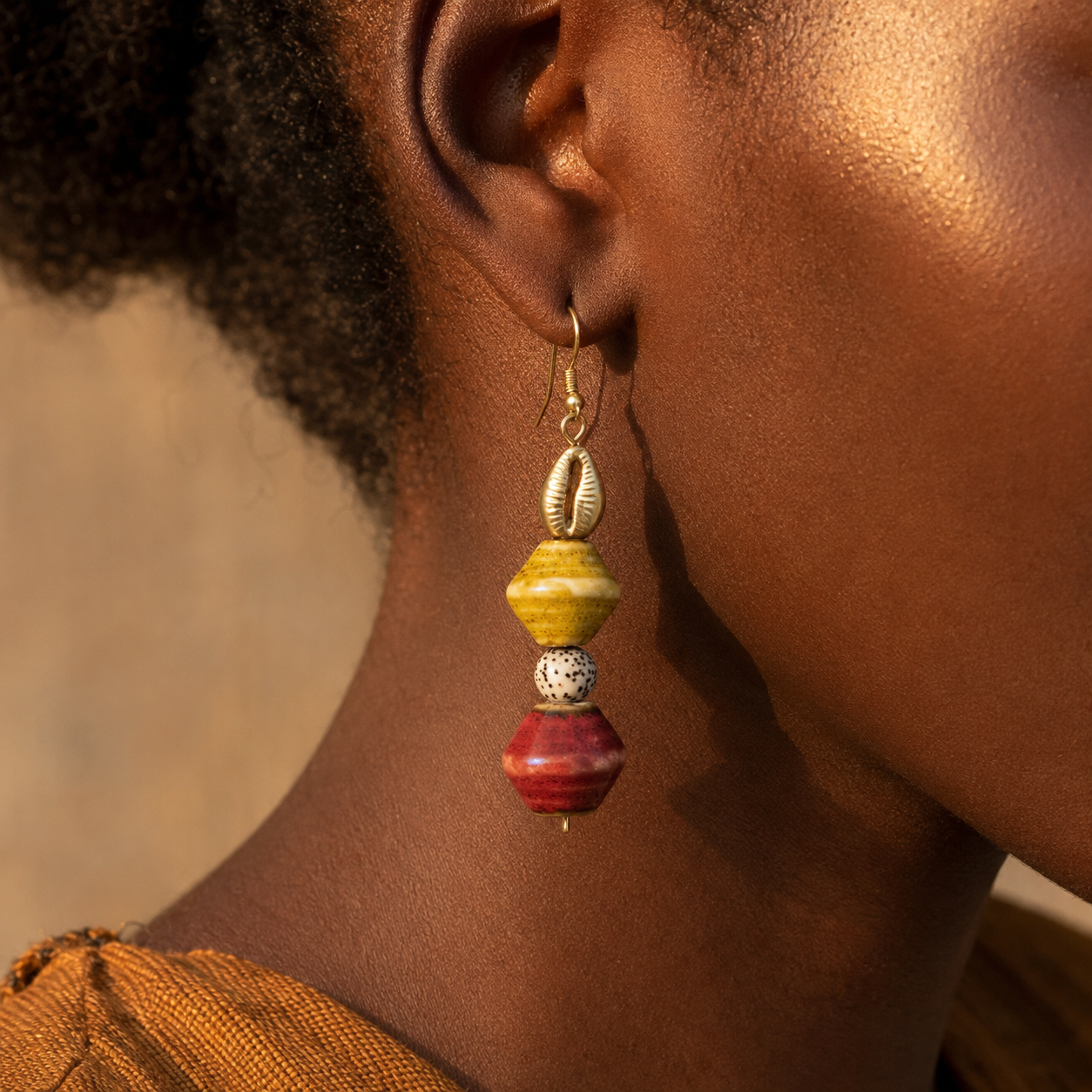 Boucle d’oreille LAKOU portée, cauri métallique et perles jaunes, rouges et mouchetées