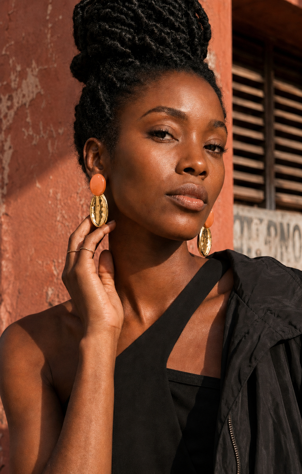Femme portant les grandes boucles d’oreilles MONA orange en résine et acier inoxydable doré